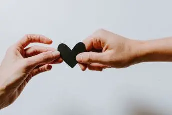 Two hands holding a heart shaped paper